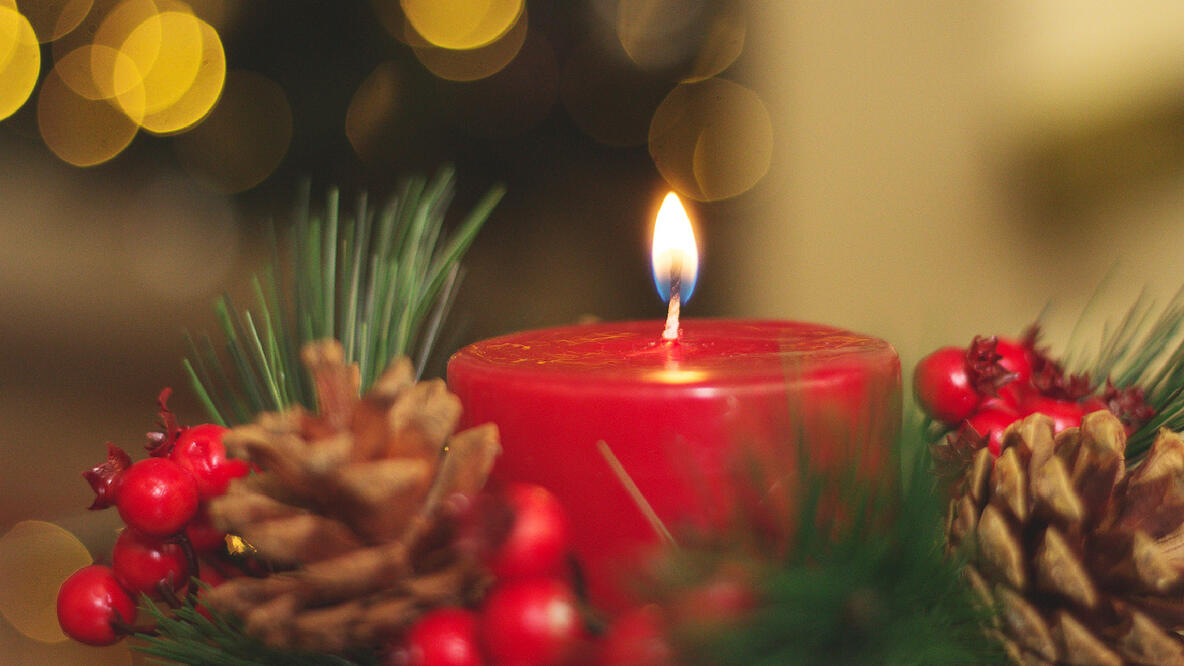 Foto: Eine rote brennende Kerze im Adventskranz