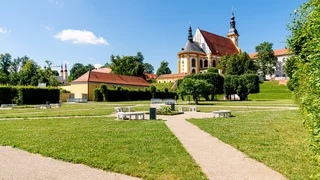 Foto: Das Kloster Neuzelle aus der Entfernung vor blauem Himmel, im Vordergund Wege, die in Richtung Kloster führen