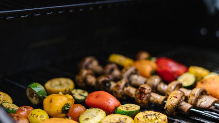 Ein Grill mit Gemüsespießen.