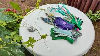 Foto: Gartenwerkzeuge und Arbeitshandschuhe auf einem runden, weißen Gartentisch