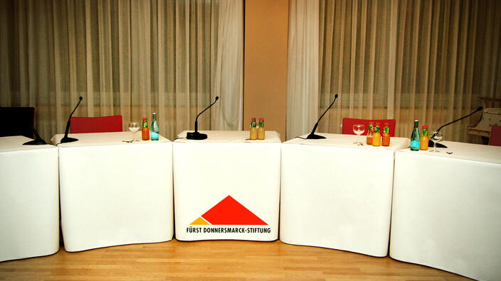 Foto: Das leere Podium in der Villa Donnersmarck, bestückt mit Getränkeflaschen und Mikrofonen