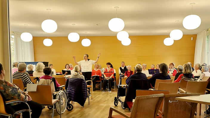 Foto: Der inklusive Chor der Fürst Donnersmarck-Stiftung beim Konzert, im Publikum und auf der Bühne mehrere Personen im Rollstuhl