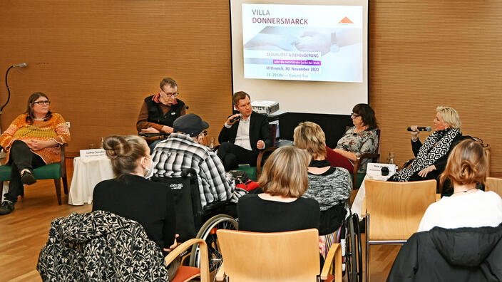 Foto von der Veranstaltung Sexualität und Behinderung: Vorne im Bild ist das Publikum, hinten das Podium zu sehen.