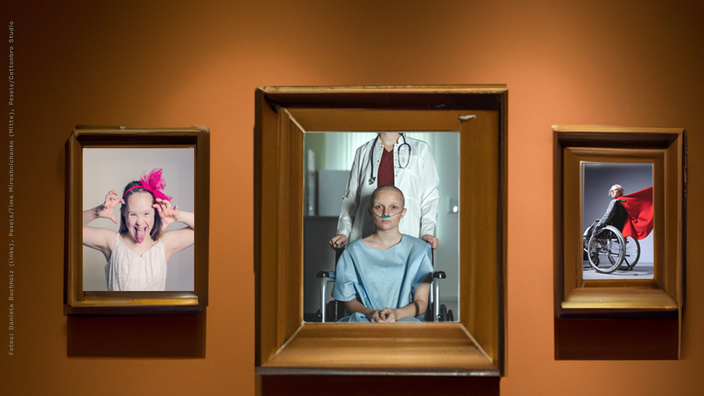 Foto: Drei Bilderrahmen auf einer braunen Wnad, links das Bild eines lachenden Mädchens mit Down Syndrom, in der Mitte eine junge Frau mit rasiertem Kopf im Rollstuhl, dahinter stehend eine Figur im Arztkittel, deren Kopf nicht im Bild ist, rechts eine junge Frau im Rollstuhl mit einem wehenden roten Cape