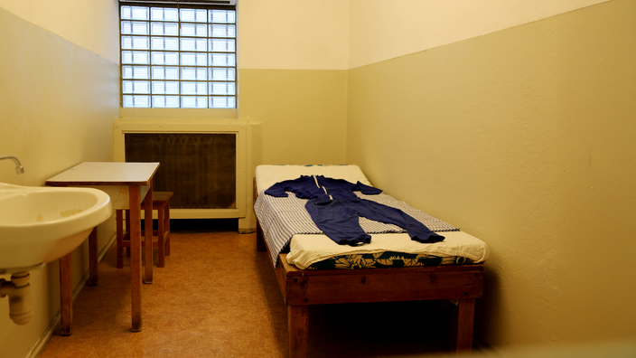 Foto: Eine karge Zelle mit Bett und vergittertem Fenster in der ehemaligen Stasi-Haftanstalt