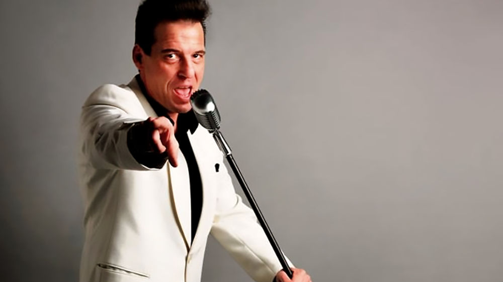 Foto: Dirk Jüttner im weißen Anzug am Elvis-Mikrophon in Pose