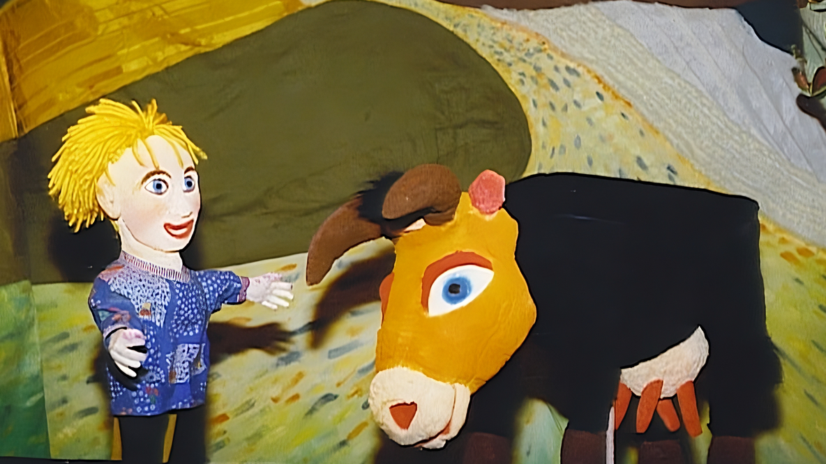 Foto: Zwei bunte Handpuppen, ein blonder Junge und eine schwarze Kuh mit gelbem Kopf vor buntem Hintergrund