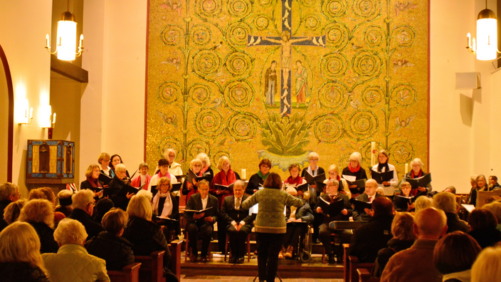 Foto: Ein gemischter Chor beim Konzert in der St. Annen-Kirche, im Hintergrund Goldfresken mit Jesus-Bild