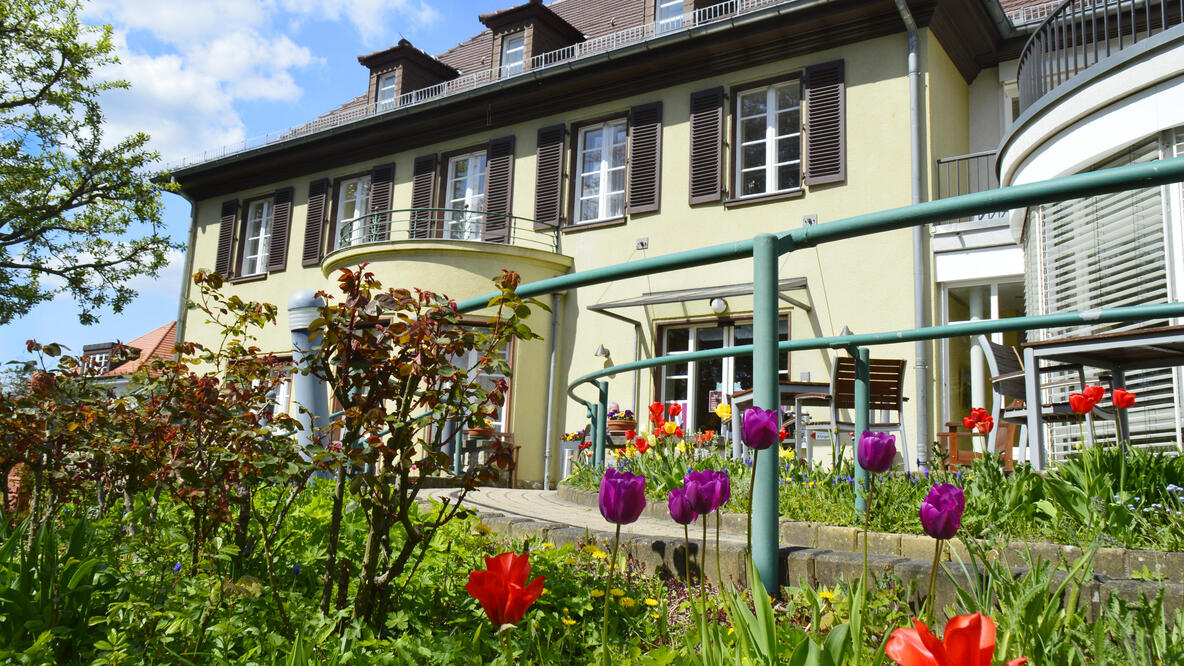 Foto: Die Villa Donnersmarck mit blühenden Blumen im Vordergrund an einem Sommertag