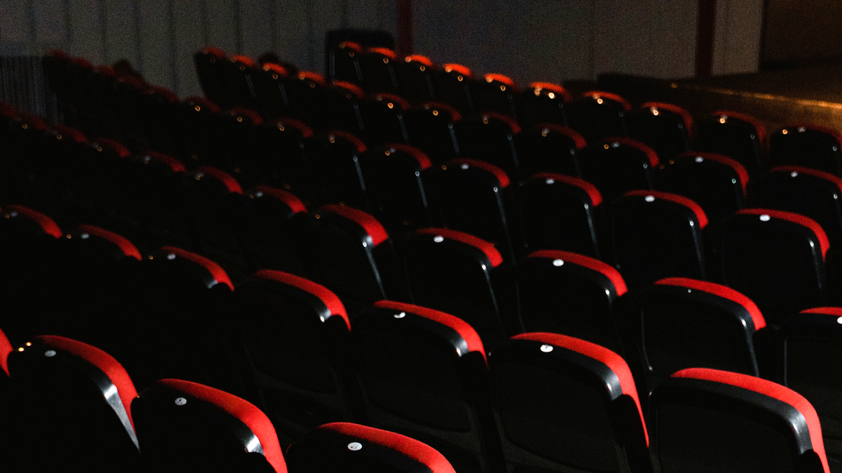Foto: Sitzreihen in einem Opernhaus, im Hintergrund im Anschnitt die Bühne